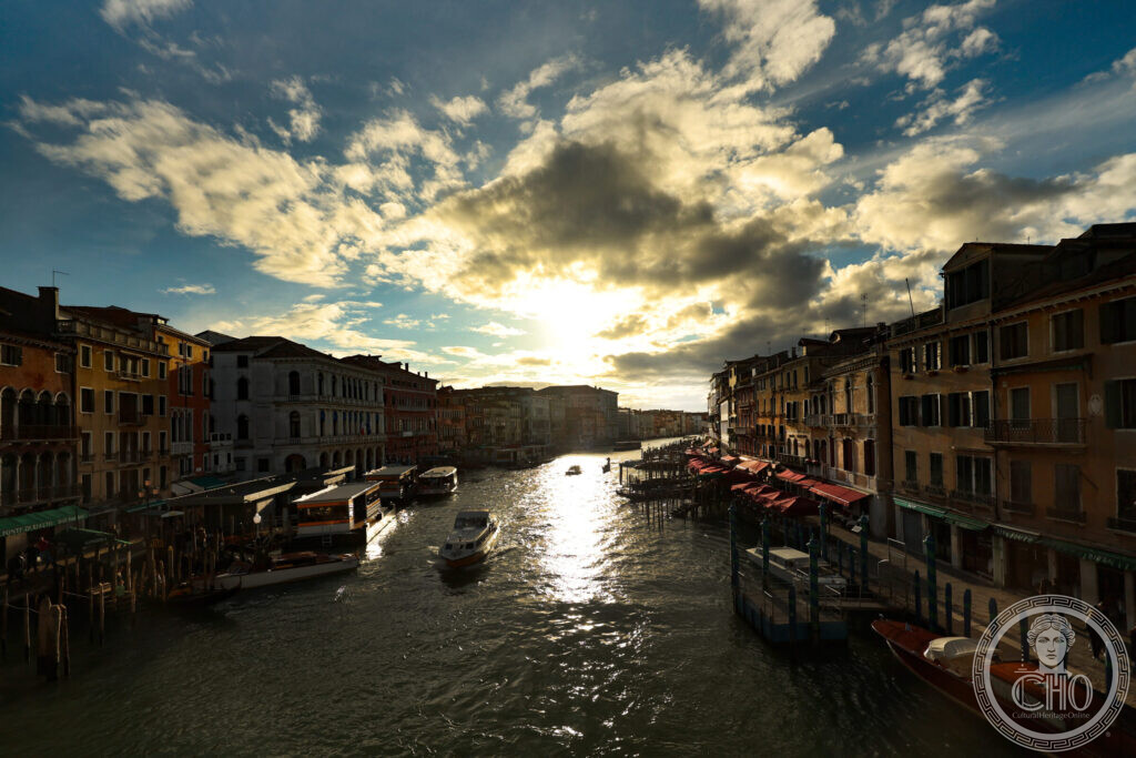 The Grand Canal at sunset from the Rialto bridge, with a gondola moored at its licensed station below