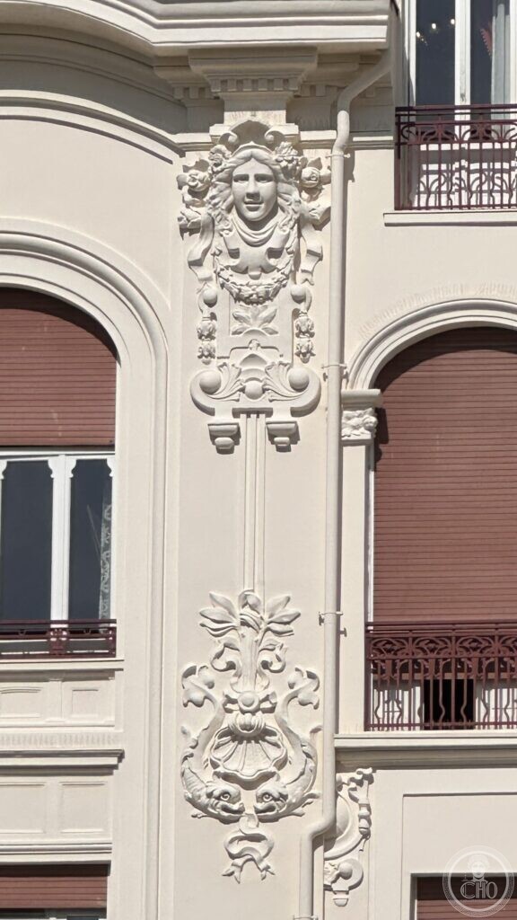 A stucco female head surrounded by flowers and garlands on the hotel facade