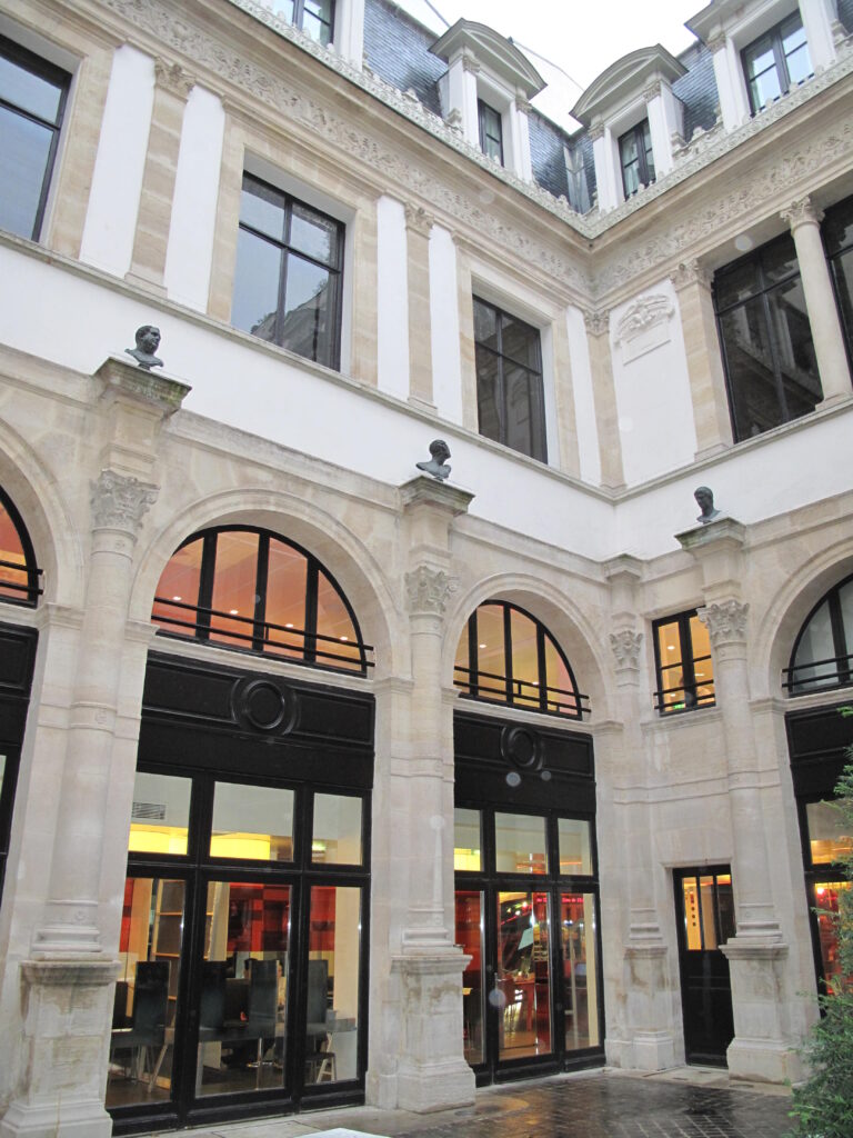 Courtyard of the Hôtel de Pourtalès, Paris: stone arcades with Corinthian capitals carrying antique-style busts, white upper floors and slate mansard