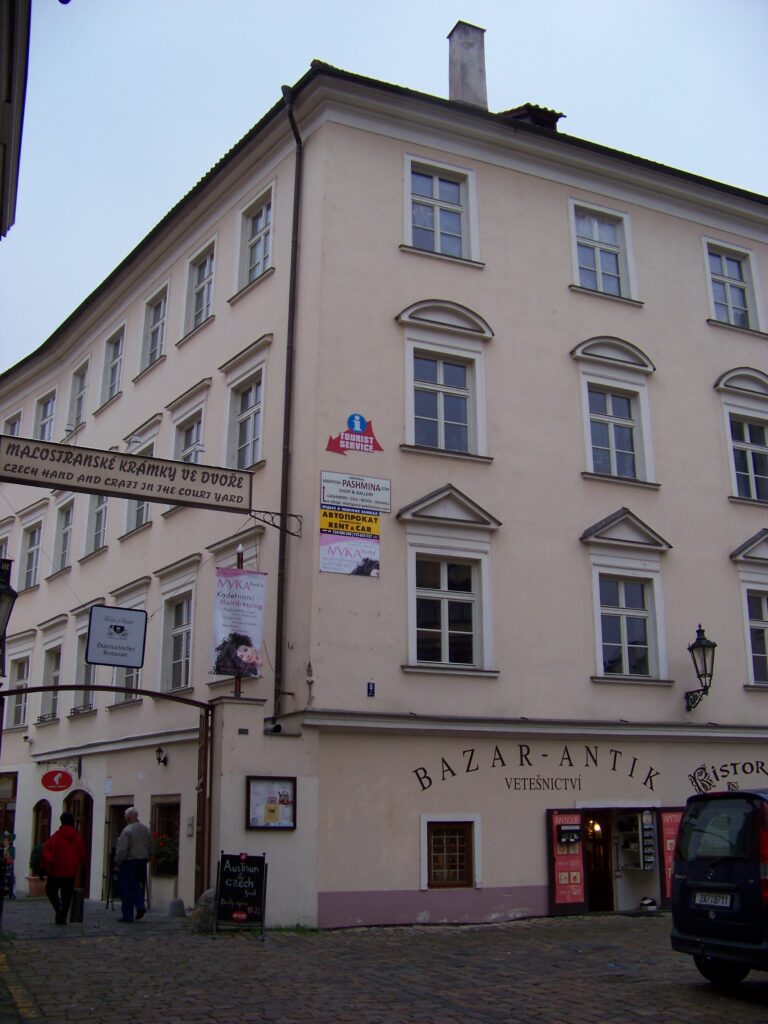 Four-storey pale house at Saská 3 in Malá Strana, Prague, with triangular and segmental pediments over the windows and small shops at street level