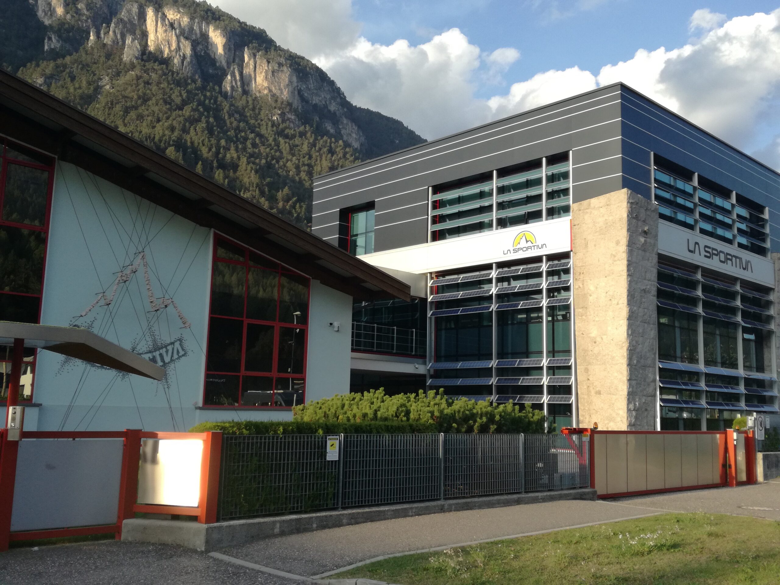 Modern manufacturing facility and headquarters of La Sportiva in Ziano di Fiemme framed by alpine pine forests