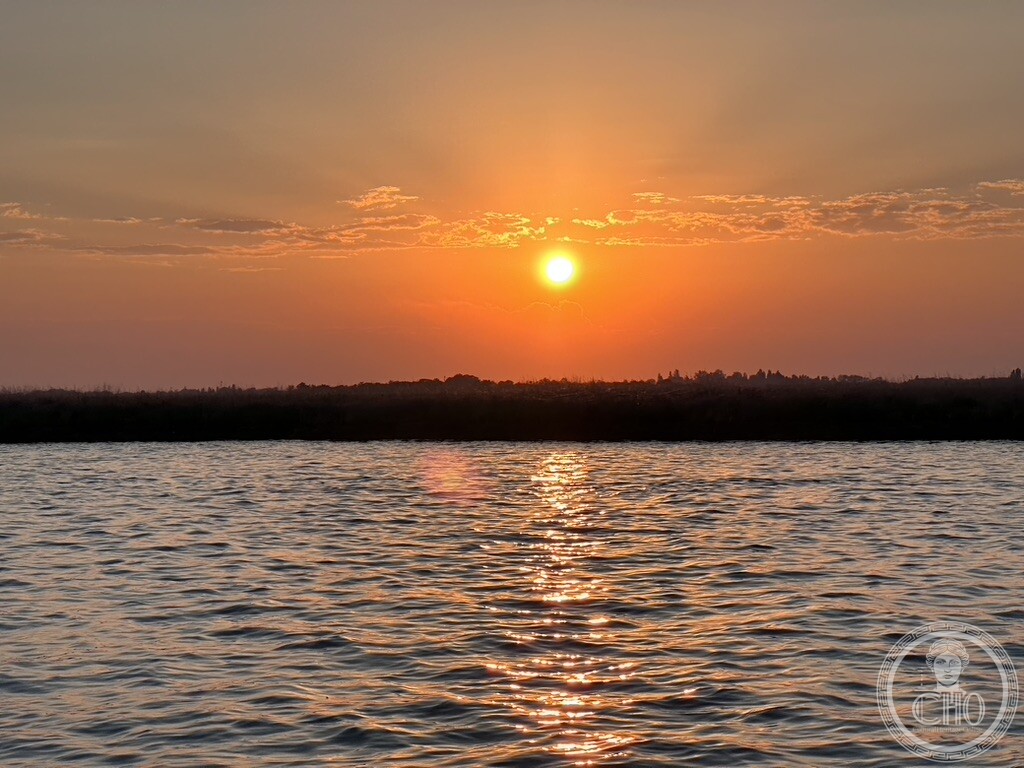 Sunset over the open water of the Venetian Lagoon, with the low profile of the mainland on the horizon
