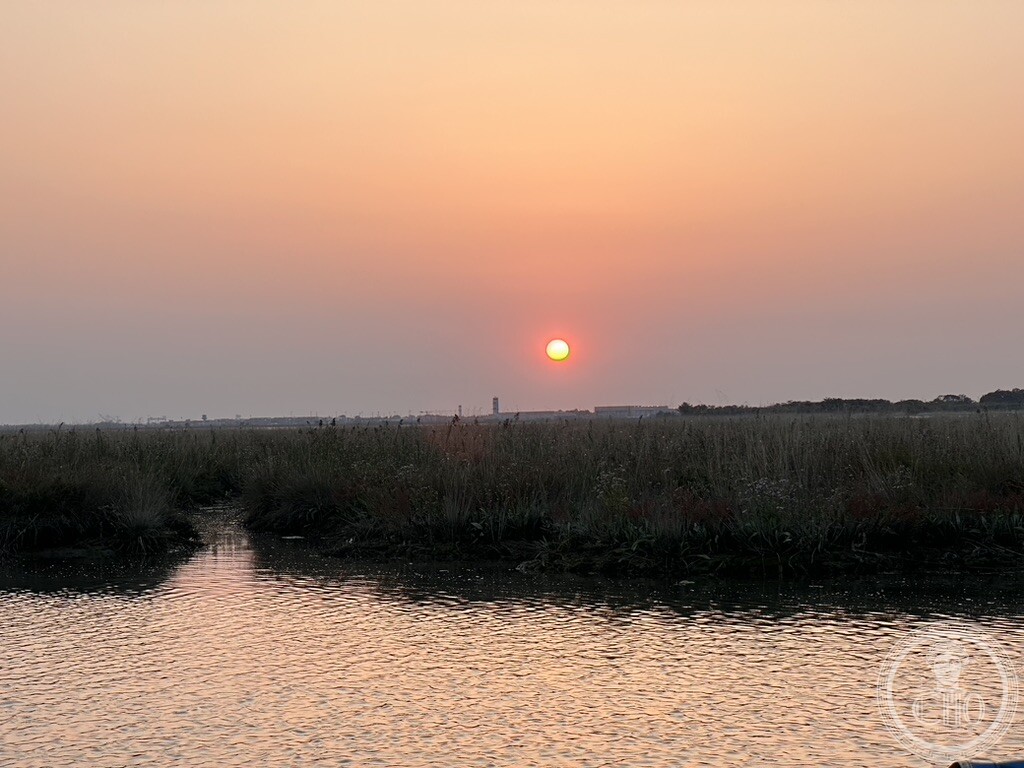 Sunset over marshland and open water in the Venetian Lagoon, with a low island on the horizon