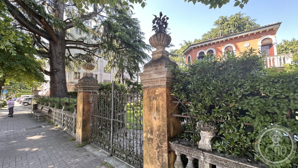 Two brick gate piers topped with carved stone urns, with a balustrade running along the garden wall