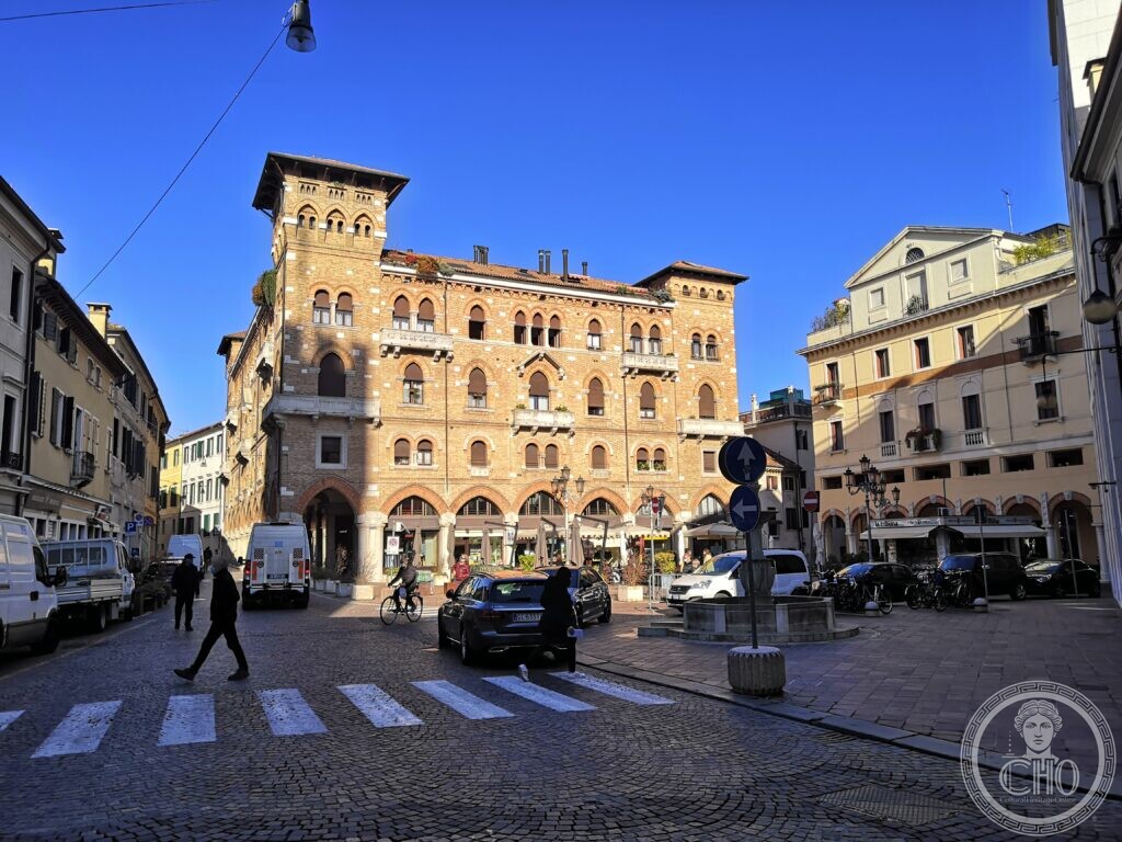 The brick facade of the Palazzo del Littorio in Treviso, with two corner towers and shops at street level