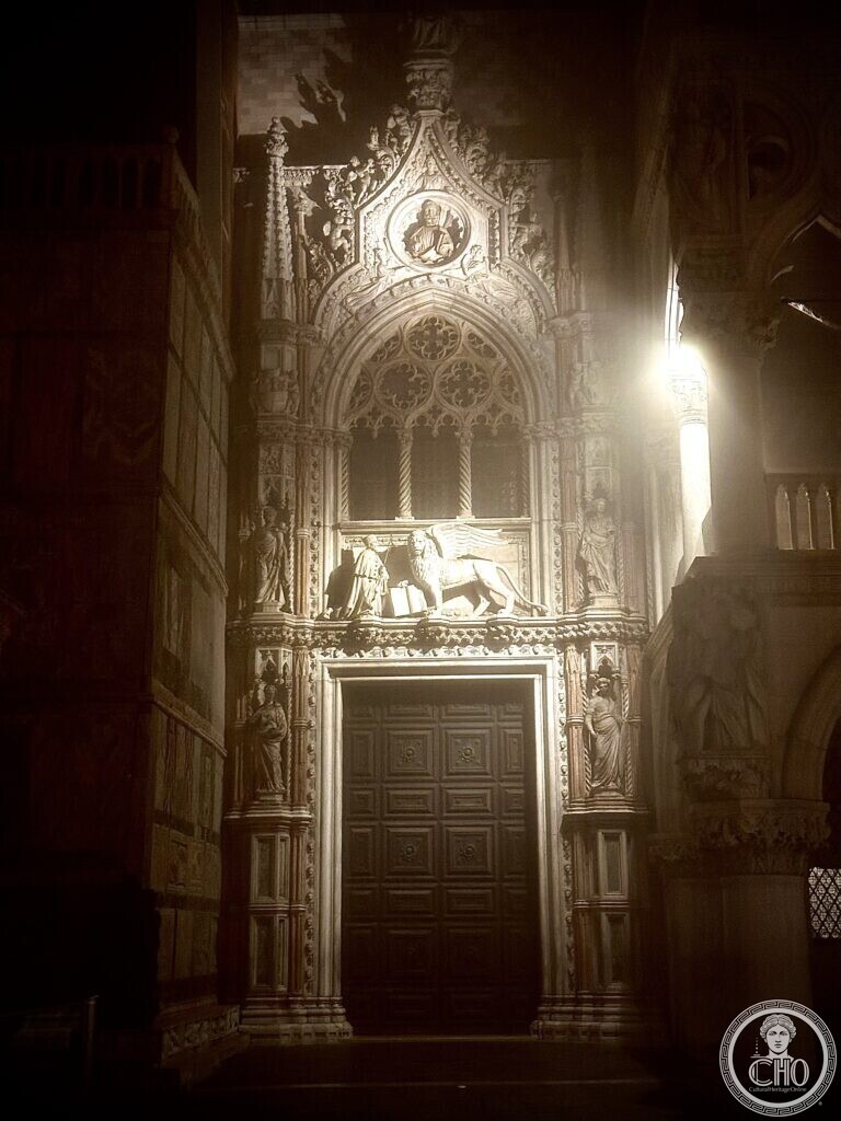 The Porta della Carta at night, the carved Gothic gate between the Basilica and the Doge's Palace, the lion of Saint Mark above the door