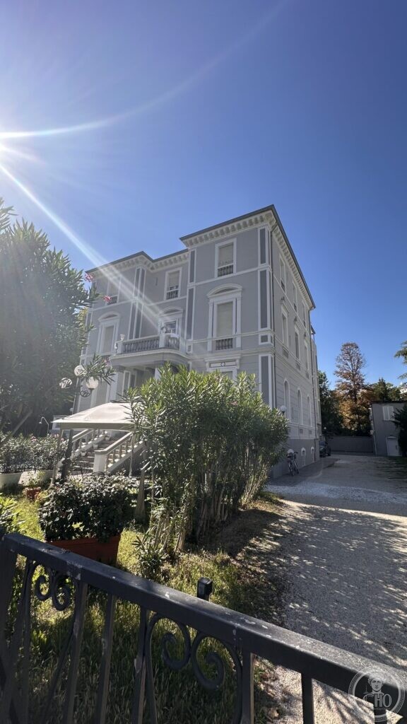 A three-storey nineteenth-century villa with rusticated quoins and pedimented windows, in a garden of oleanders