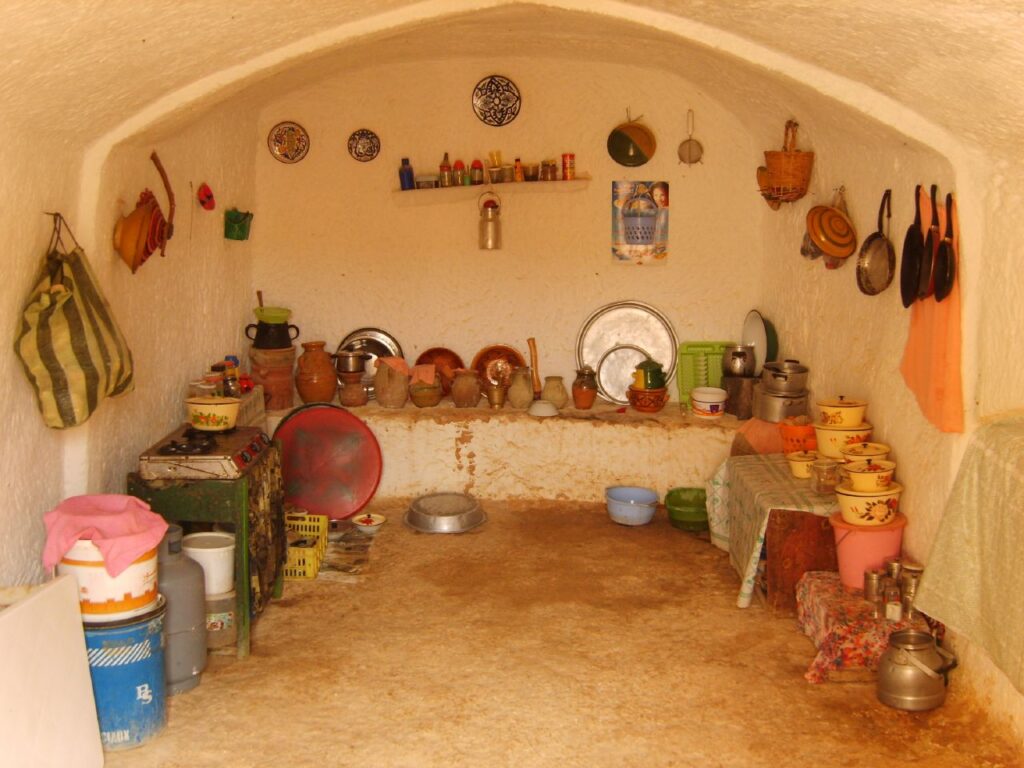 The carved kitchen of a Matmata troglodyte house, lined with traditional pottery, pans and a gas stove