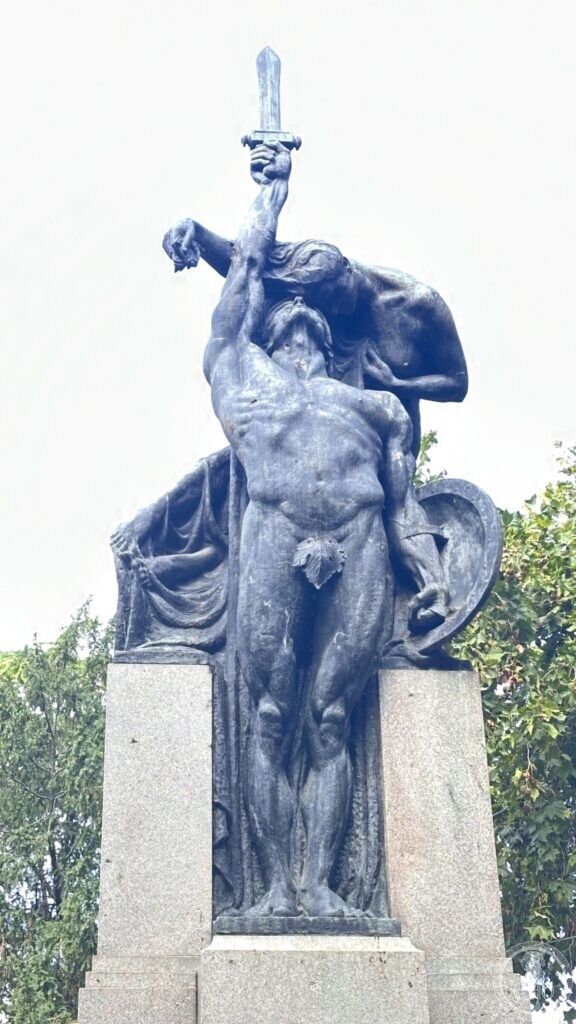 Bronze group of a naked warrior with a shield and a draped winged figure raising a sword above him