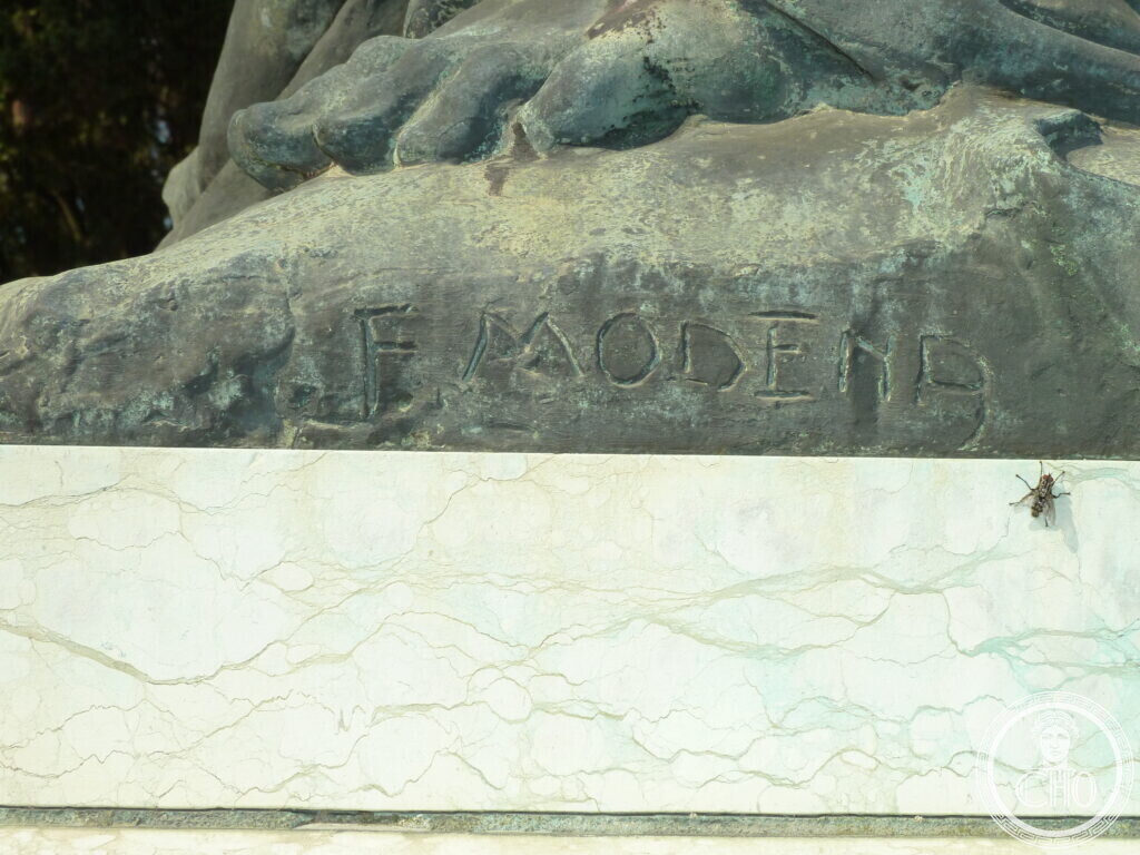 The sculptor's signature, F. MODENA, carved into the bronze at the base of the figure group