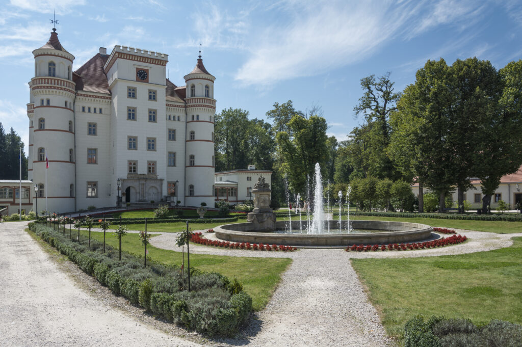 Wojanow Palace in Lower Silesia, its pale neo-Gothic facade with corner towers seen from the park