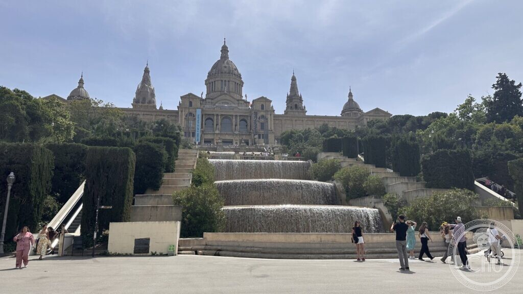 Water cascading down stepped basins below the Palau Nacional, with visitors walking past
