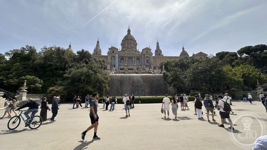 The domed Palau Nacional seen from the esplanade below, with people crossing the open square