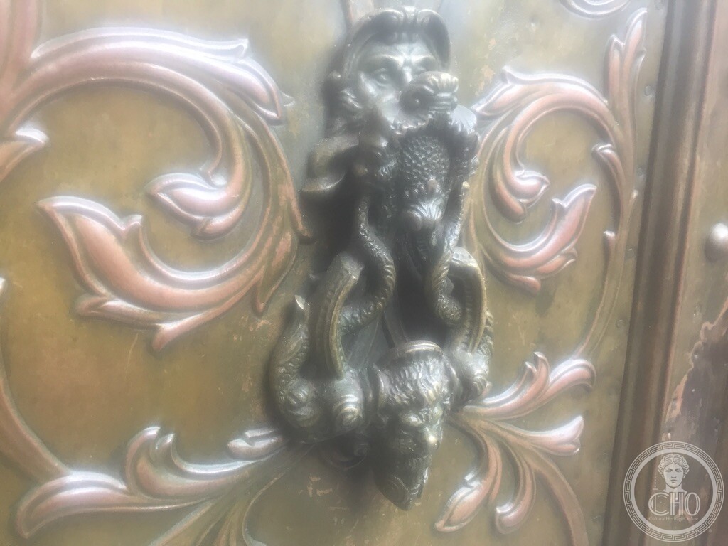 Antique patinated bronze door knocker with mythological triton, dolphin and grotesque mask on the door of Palazzo Bollani Erizzo, Venice