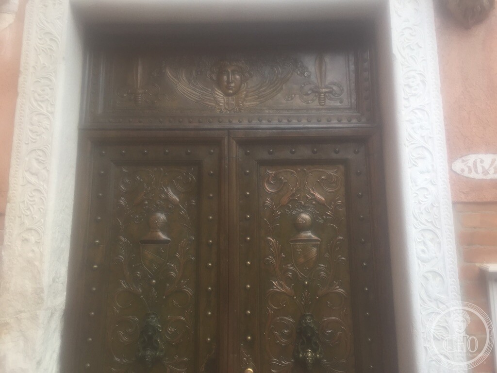Monumental carved wooden entrance door framed by sculpted stone with heraldic crests at Palazzo Bollani Erizzo, Venice