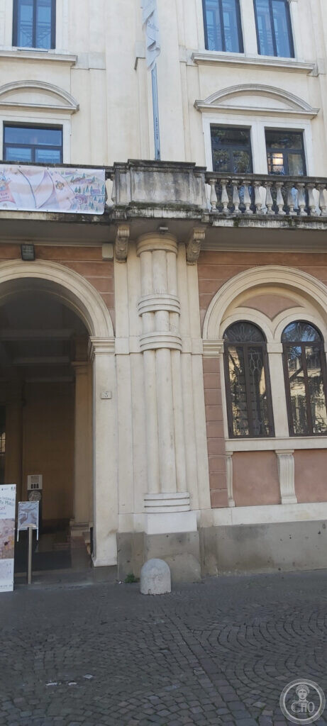 The entrance of Palazzo Santo Stefano in Padua: a giant fluted column with banded rustication beside the arched doorway, under a stone balcony with a balustrade