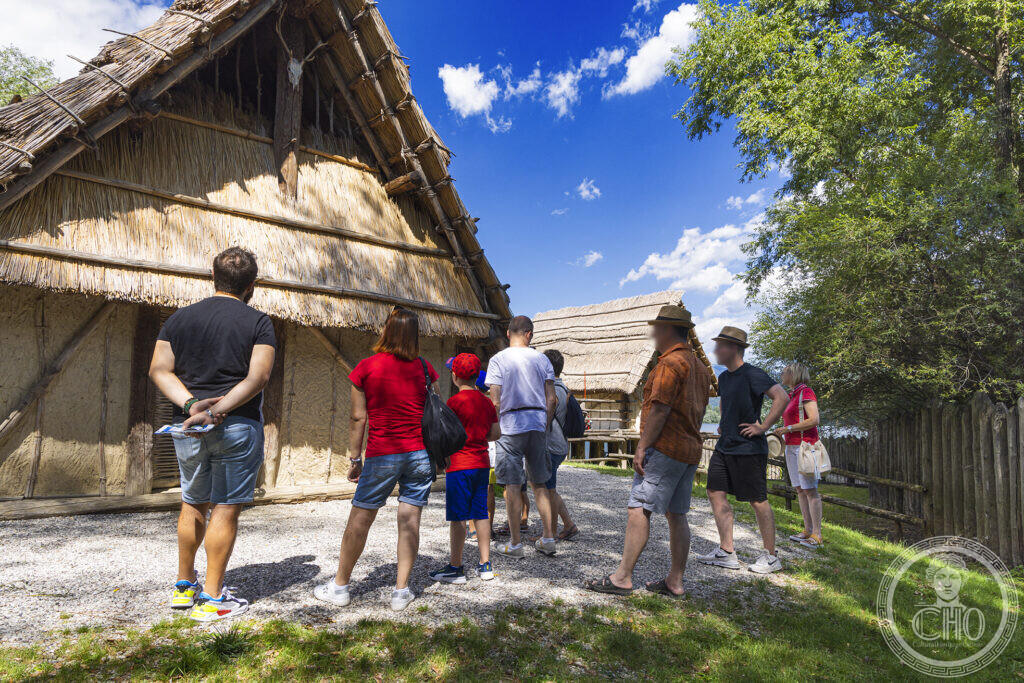 Visitors during the guided tour in front of the first pile-dwelling of the Livelet park
