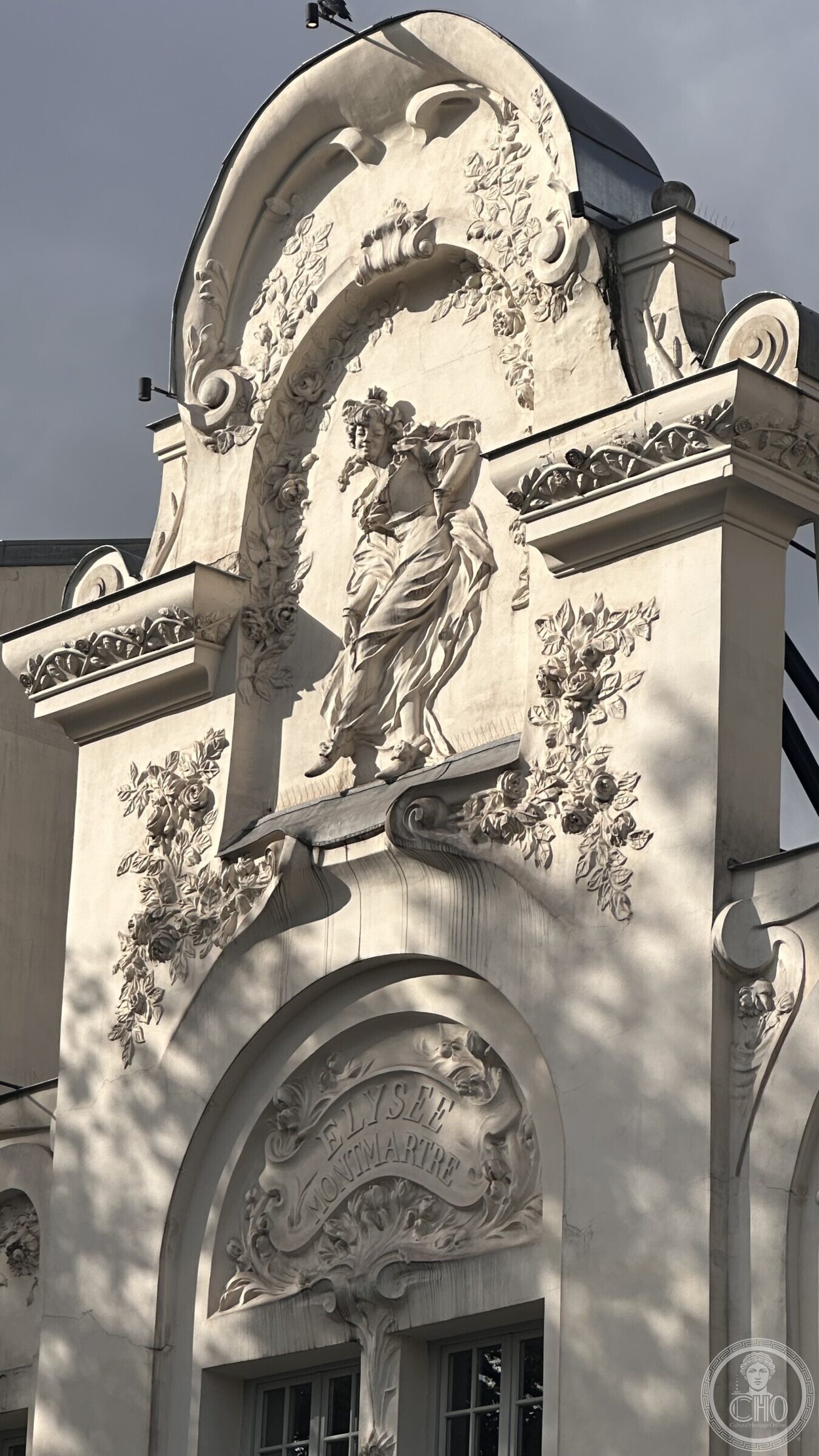 Pediment of the Élysée Montmartre with a female figure in staff among garlands of roses