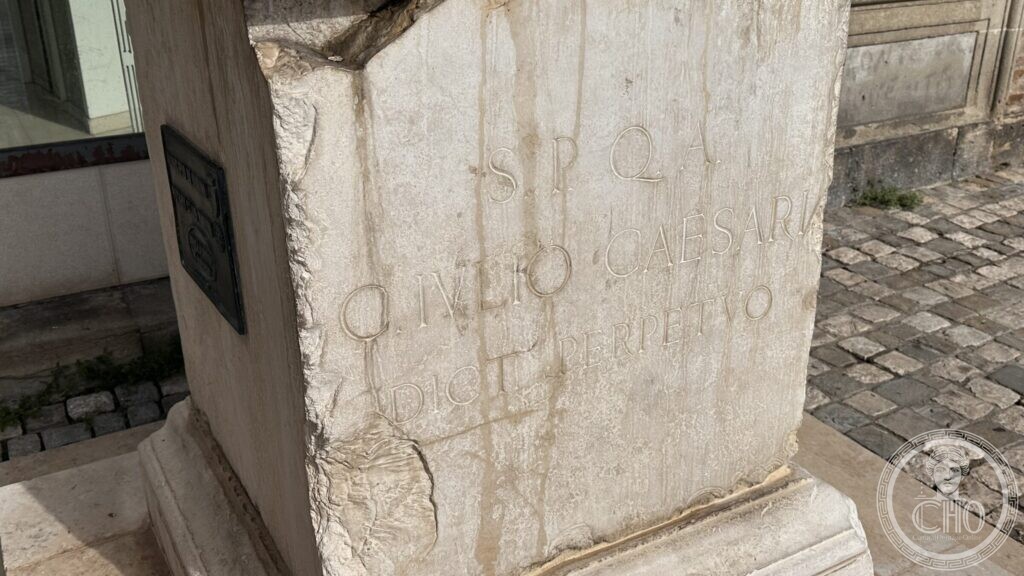 Weathered inscription on the statue pedestal reading S.P.Q.A. C. IVLIO CAESARI DICT. PERPETVO