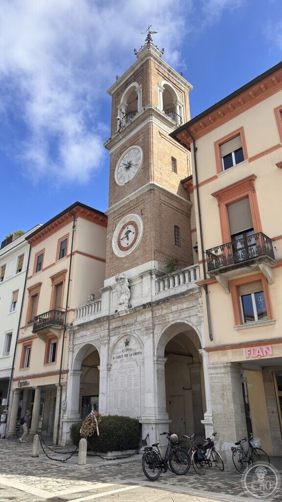 The clock tower with a white clock face above and a round painted calendar dial below