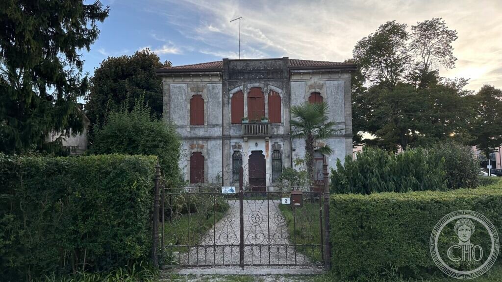 The villa seen from the wrought-iron gate through the hedged front garden