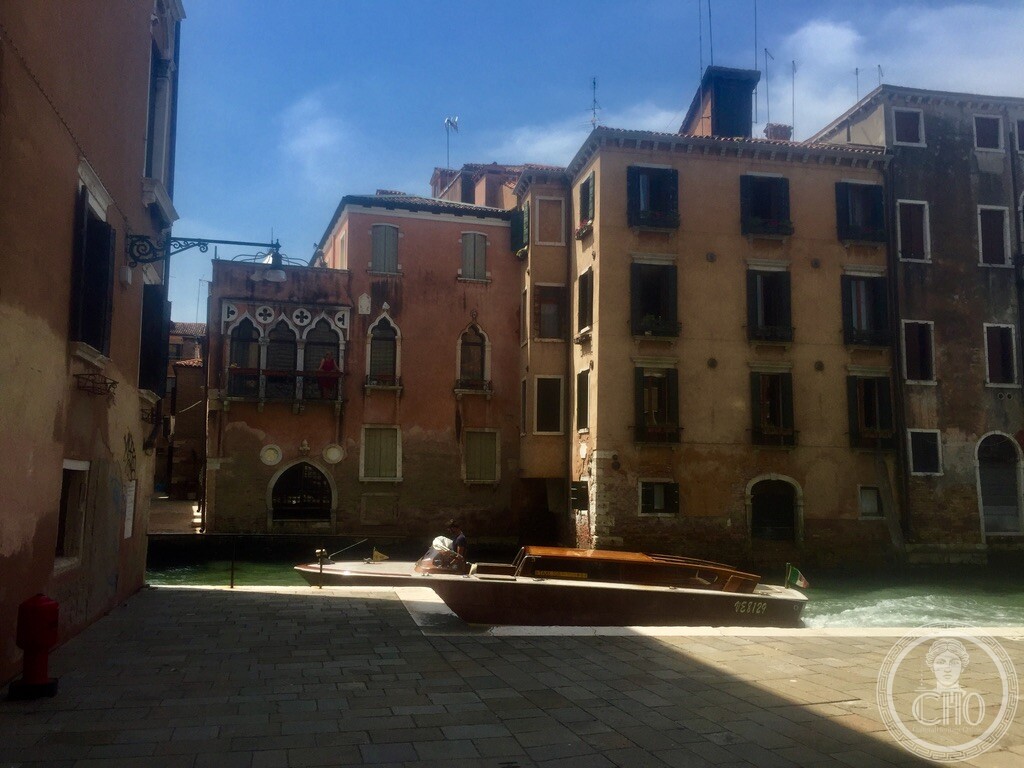 Canal perspective along Rio de San Pantalon showing a wooden water taxi and the Gothic windows of Palazzo Secco Dolfin in Venice