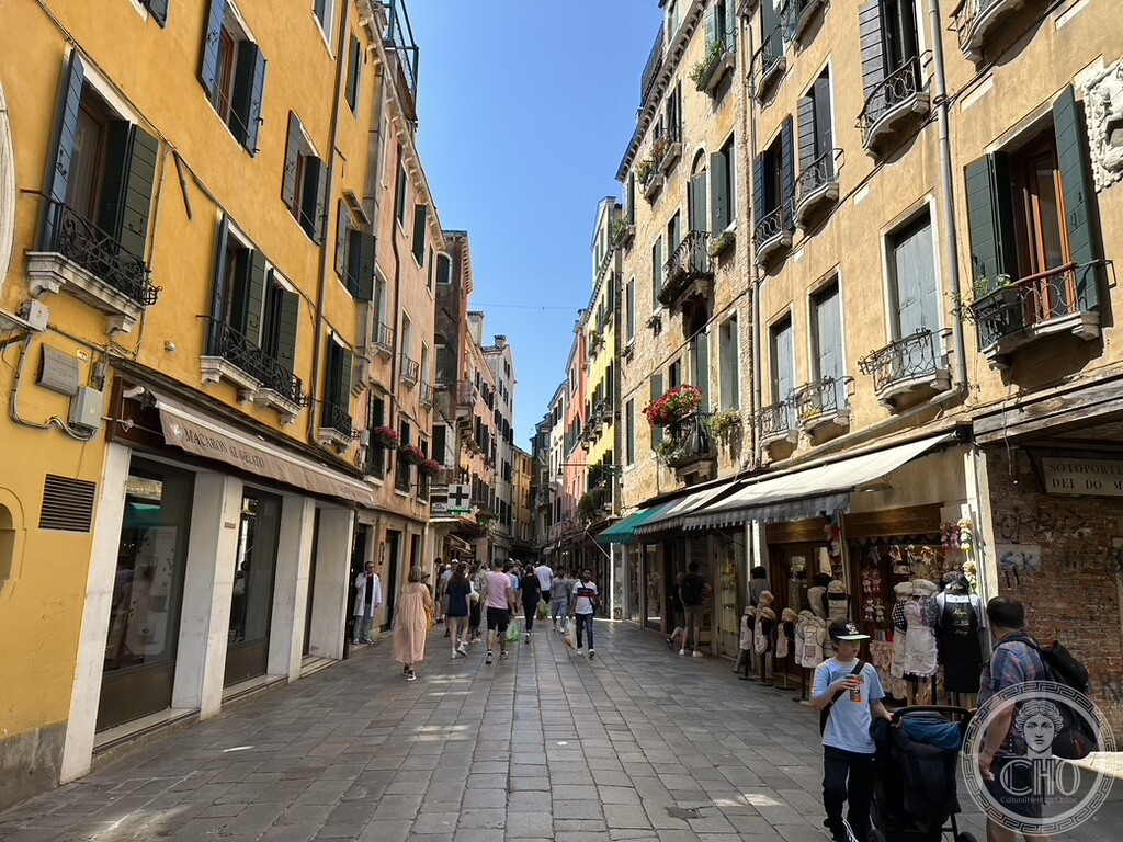 Sunlit perspective down the bustling shopping thoroughfare of Ruga Vecchia San Giovanni with historic facades and shopfronts in San Polo Venice