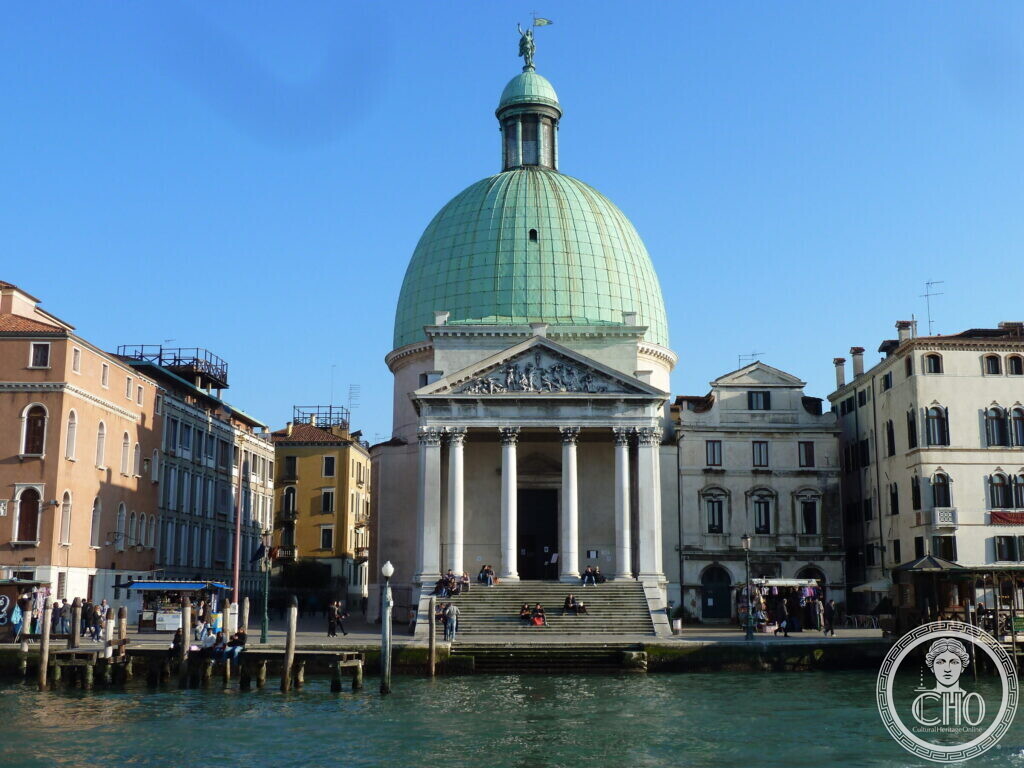 A domed church with a columned temple front and wide steps down to the Grand Canal, people sitting on the steps