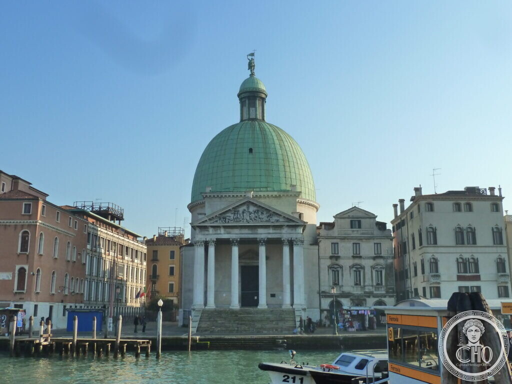 The columned temple front and green copper dome of San Simeone Piccolo seen across the Grand Canal, a water-bus stop in the foreground