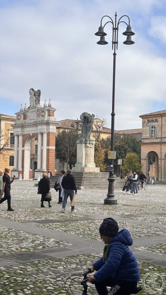 The Ganganelli arch and the war memorial seen across Piazza Ganganelli, with a lamp standard in the foreground