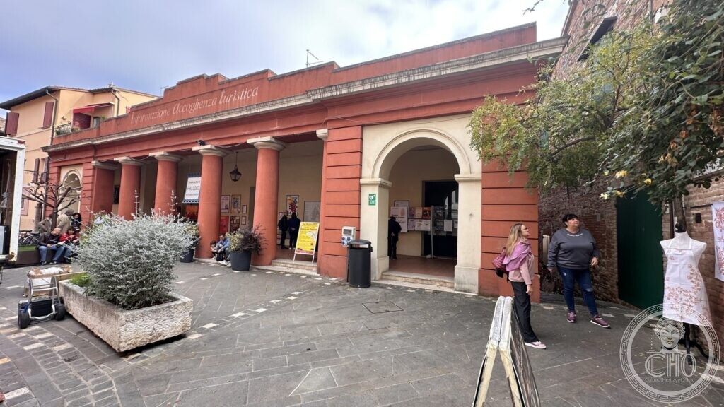 The Pro Loco building in Santarcangelo di Romagna, a red portico with columns, with Informazione Accoglienza turistica painted in script along the entablature