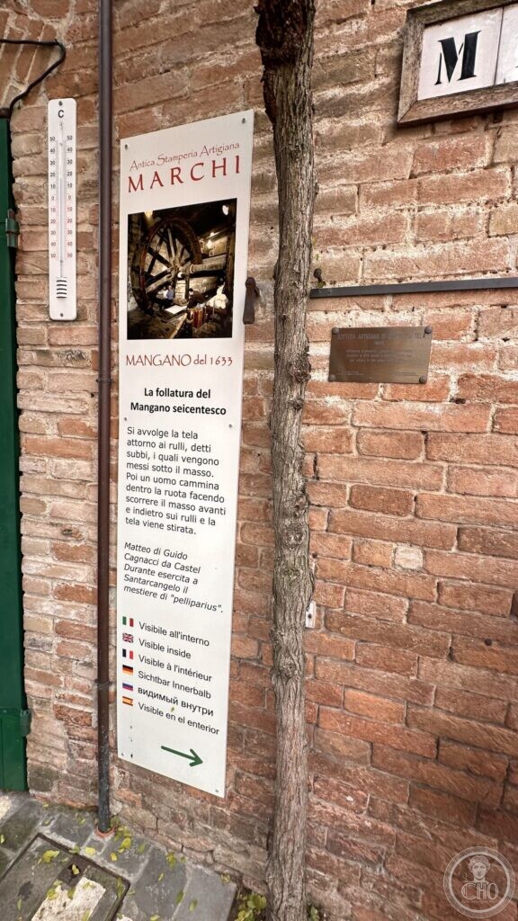 The explanatory panel beside the door of the Stamperia Marchi, describing the seventeenth-century mangano, with a bronze tablet dated 1633 on the wall