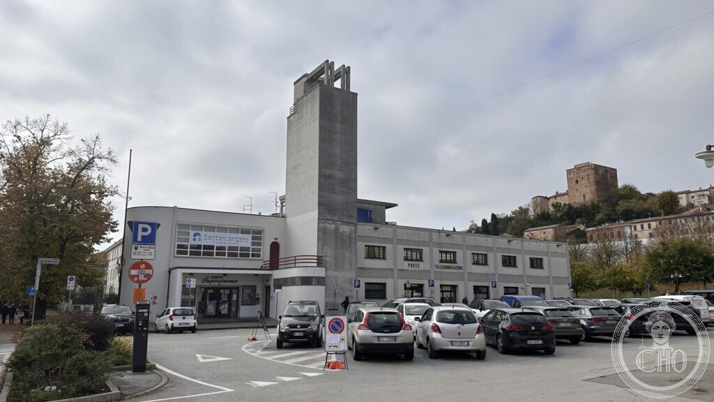 The Supercinema and the post office block at Santarcangelo di Romagna seen across the car park, with the hill town and the castle behind