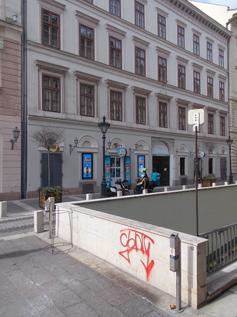 Pale three-storey Classicist street front with arched ground-floor openings and framed windows, Sas utca 12, Budapest