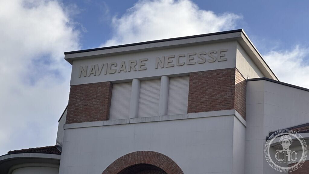 Close view of the raised letters NAVICARE NECESSE across the top of the tower against the sky