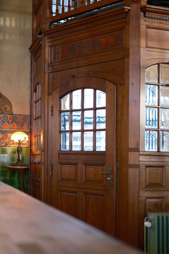 Pitchpine joinery and a glazed door lettered Uitgang in the Jugendstil waiting room, Haarlem station