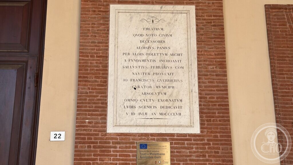 Marble plaque with a fourteen-line Latin inscription set in the brick wall under the portico