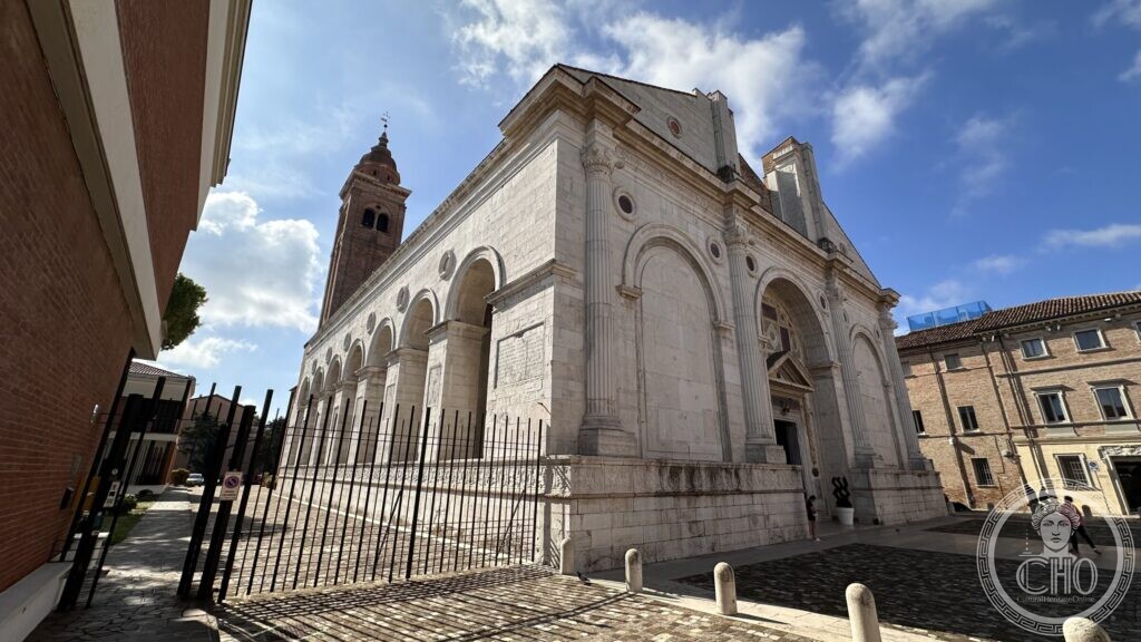 The row of deep arcades along the side of the Tempio Malatestiano, with a brick bell tower behind