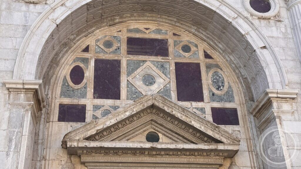 Lunette above the main door inlaid with dark red and green stone discs and squares in white frames
