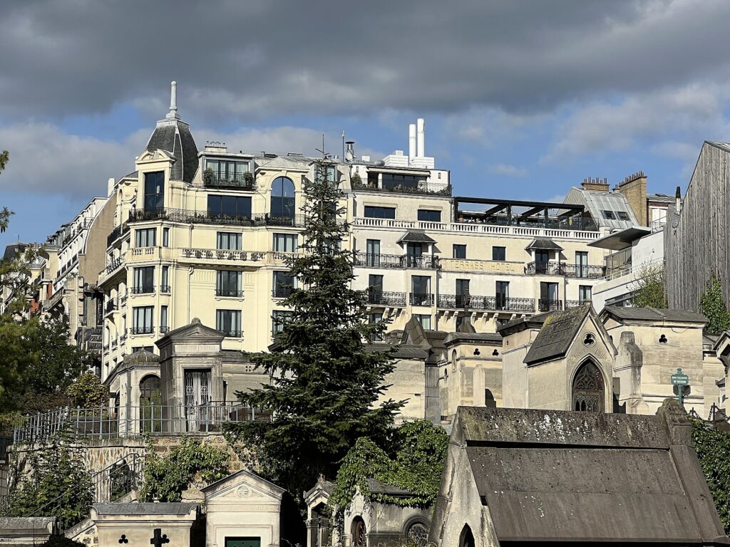 Cream-coloured front of the Terrass Hotel at 12-14 rue Joseph-de-Maistre, Paris, seen from the Montmartre Cemetery, with a corner pavilion under a slate dome, long iron balconies and the painted name Terrass Hotel on the right wing