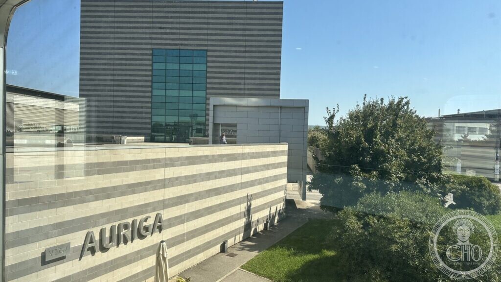 A glass-fronted office block named Auriga, seen across a lawn inside the VEGA science park