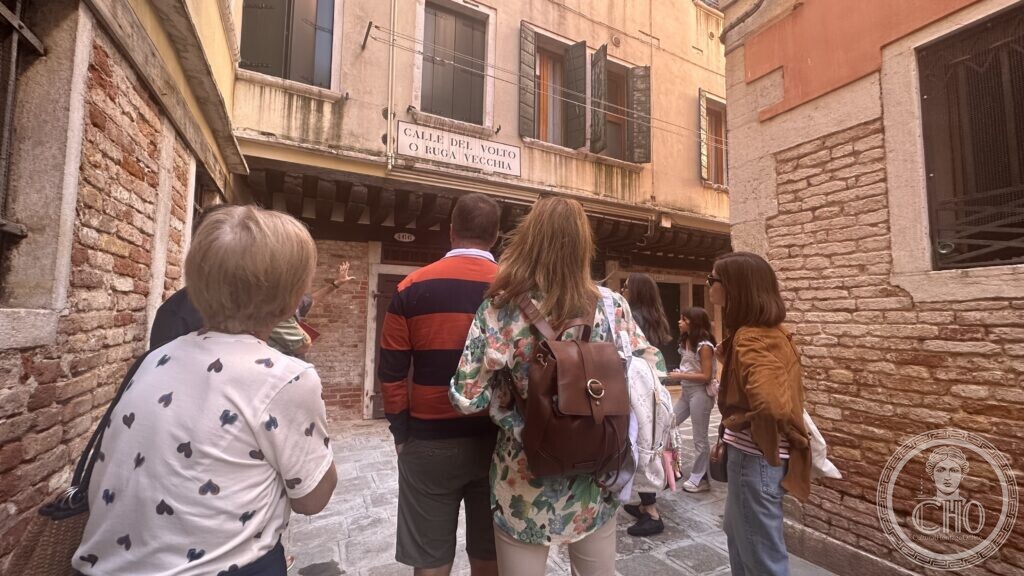 The street sign of Calle del Volto o Ruga Vecchia above a sottoportego, walkers beneath it