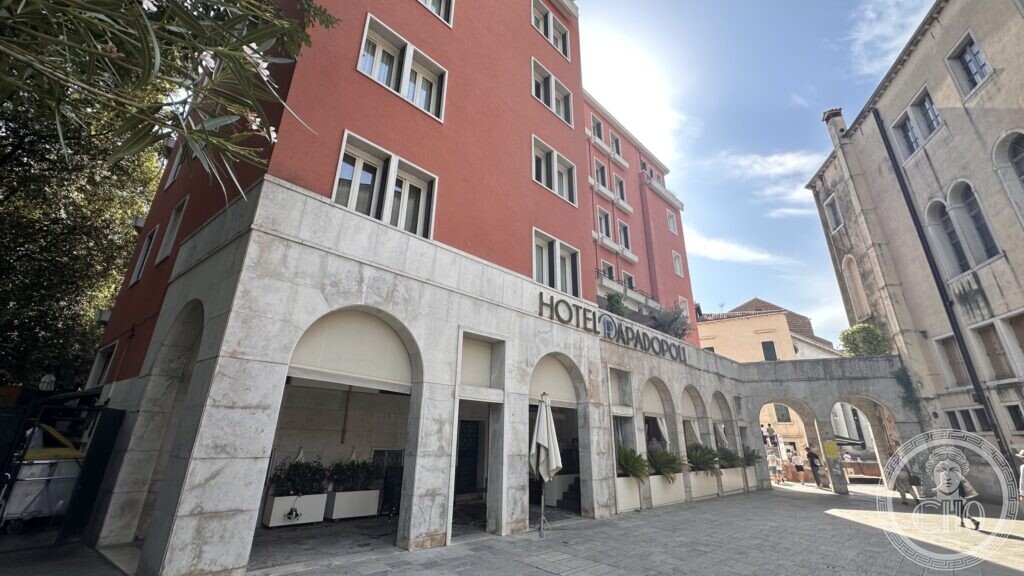 The white stone arcade at the foot of the Hotel Papadopoli, with the hotel name in metal letters above the round arches