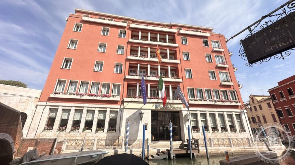 The canal front of the Hotel Papadopoli: a symmetrical pink elevation with a stone water entrance and three tiers of recessed loggias in the centre