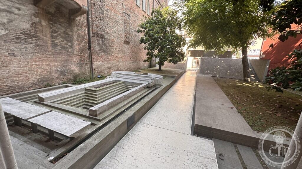 A Gothic portal of Istrian stone laid flat in a shallow basin of water in the courtyard of the Iuav, against the bare brick flank of the old convent