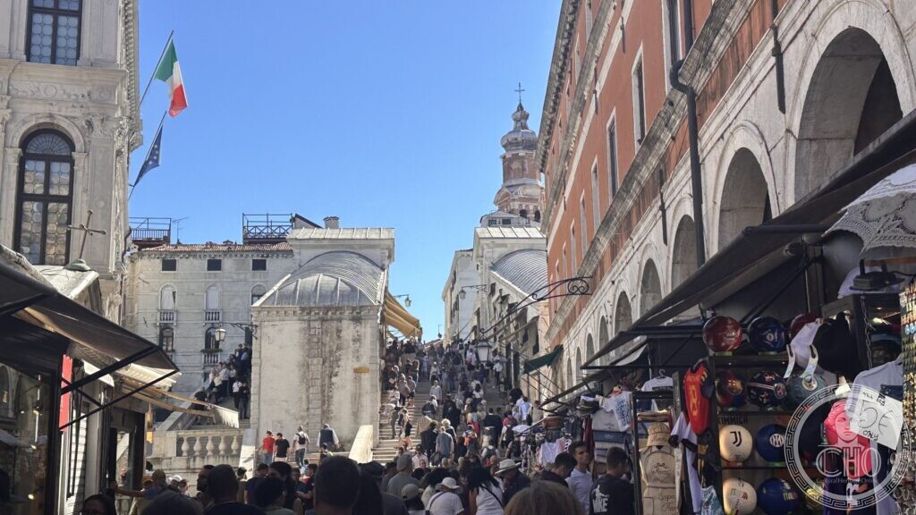 The Rialto bridge crowded with people, seen from the foot of the ramp
