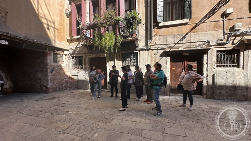 A group standing in a small paved Venetian campo between old houses