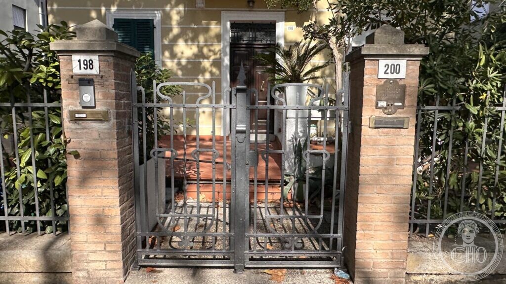 The front of the villino with plane trees casting shadows across the brickwork