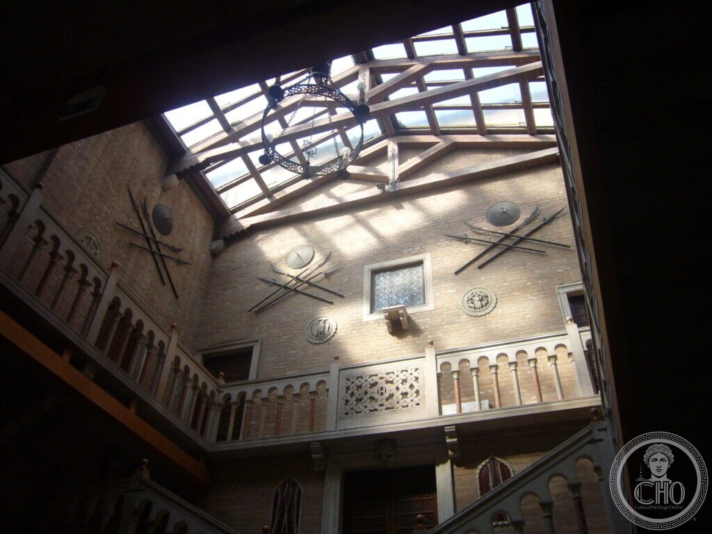 Upward view of the inner court of Villa Hériot with timber-and-glass skylight and panoplies of shields and halberds