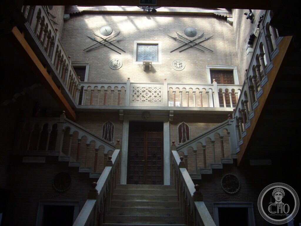 Inner court of Villa Hériot with symmetrical double staircase, colonnaded balustrades and trophy panoplies on the brick walls